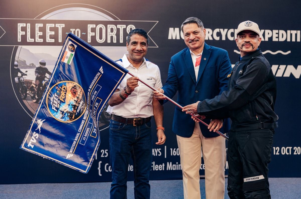 An outside image showing TVS Business Head Mr Vimal Sumbly, Vice Admiral Rahul Vilas Gokhale, and Captain Shekhar Deshpande holding the flag for the event