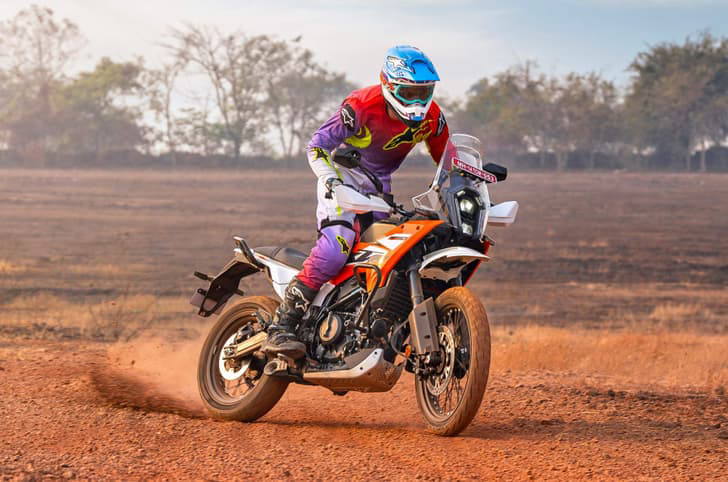 Rider power-sliding a KTM 390 Adventure on barren dirt land