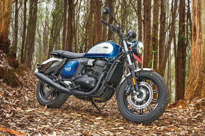 Jawa 42 FJ parked amongst trees with fallen, dry leaves on the ground