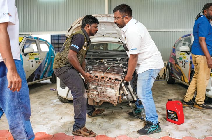 Two people carrying away an engine block.