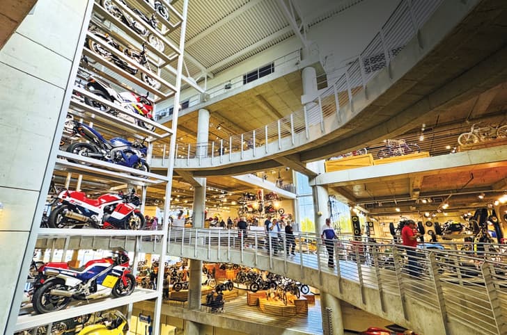 Image from the Barber Vintage Motorsports Museum with bikes stacked on the left of the image, and people walking on the right side