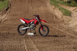 The Ducati Desmo250 MX pictured on a stand at a motocross track.