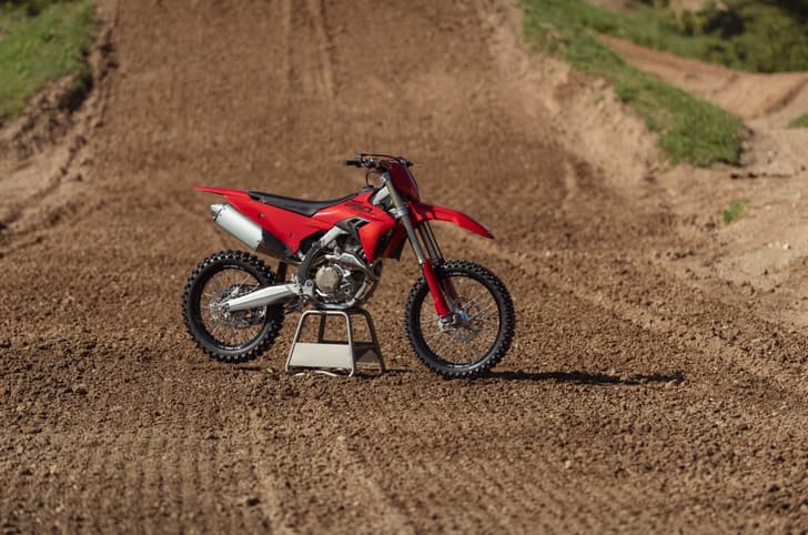 The Ducati Desmo250 MX pictured on a stand at a motocross track.
