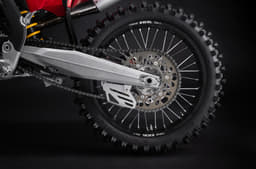 Rear wheel assembly showing the aluminium swingarm, chain drive and spoked wheel.