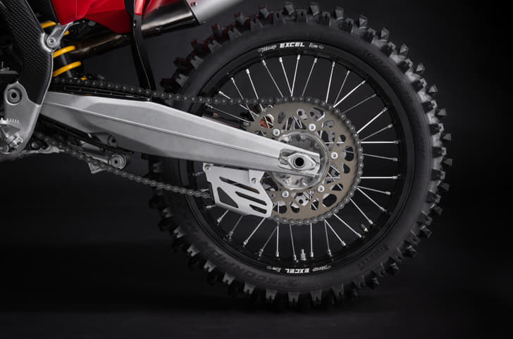 Rear wheel assembly showing the aluminium swingarm, chain drive and spoked wheel.