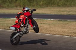 Outside image showing a wheelie being performed on the Ducati Desmo450 SM at a racetrack.