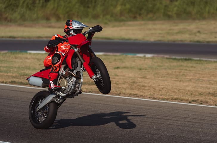 Outside image showing a wheelie being performed on the Ducati Desmo450 SM at a racetrack.