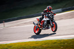An outside image showing the KTM 990 Duke R performing a left lean with the front wheel slightly off the ground.