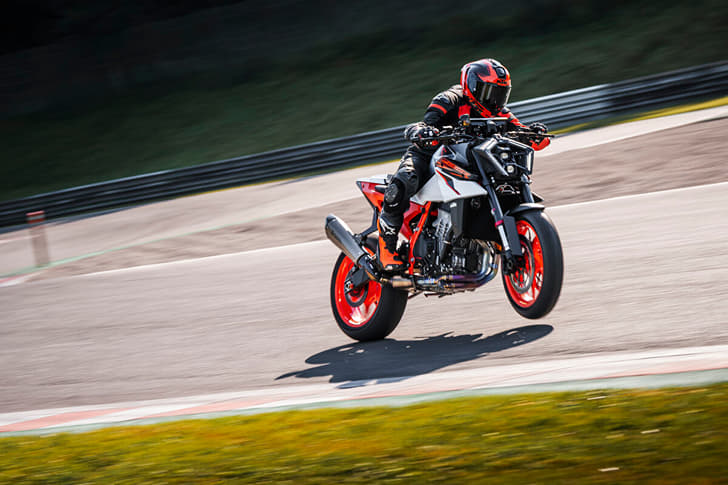 An outside image showing the KTM 990 Duke R performing a left lean with the front wheel slightly off the ground.