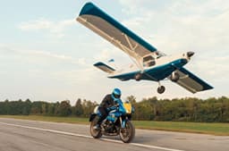 Yamaha XSR900 GP Legend Blue riding alongside a flying small airplane.