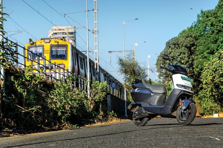Ather Rizta front right side static in city with train passing in background